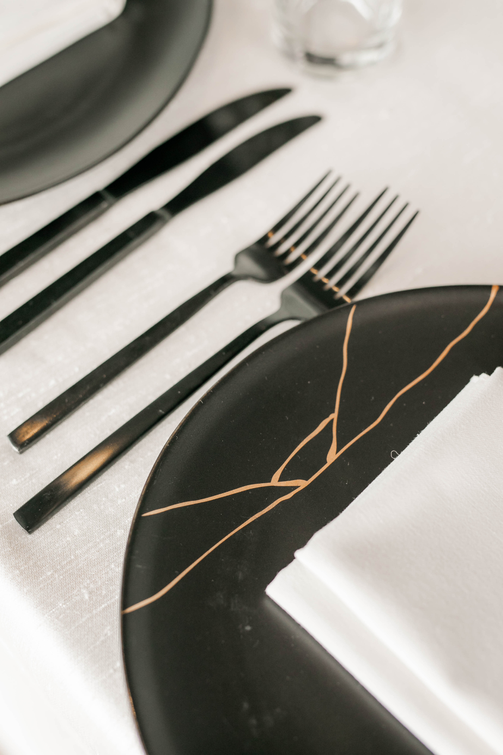 closeup of black flatware and black plates with gold detail as part of wedding decor