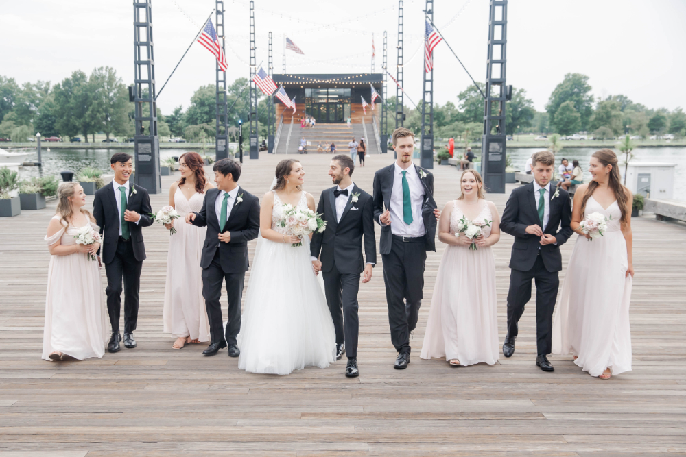 bride and groom walk with wedding party down DC pier