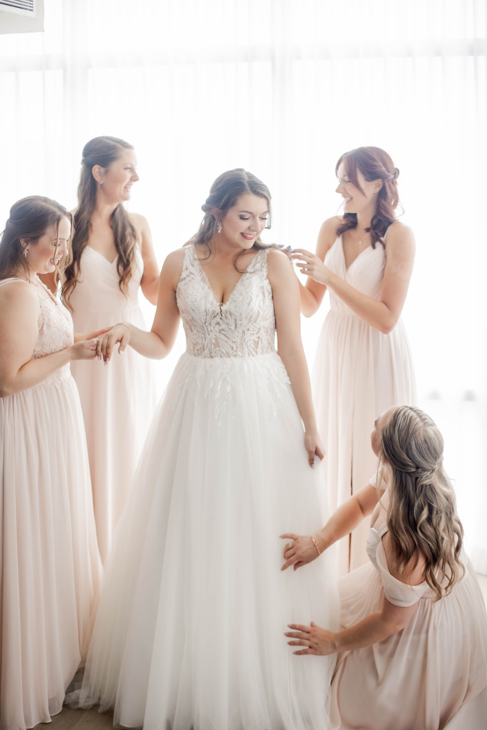 bridesmaids help bride into her dress before wedding at La Vie