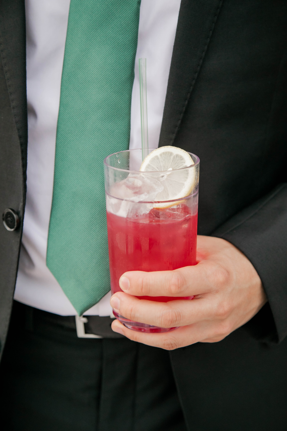 groom holds red signature cocktail