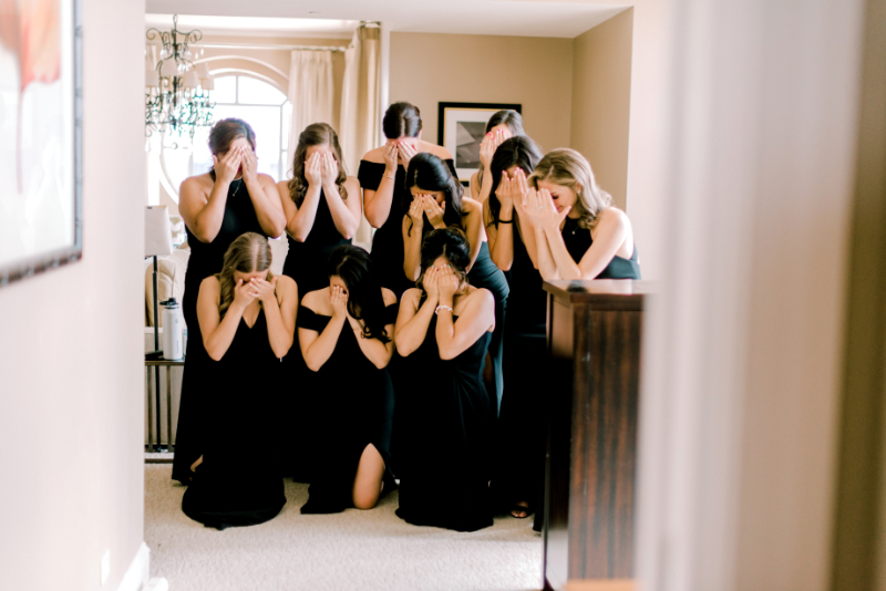 bridesmaids in black bridesmaid dresses close eyes for bridal reveal