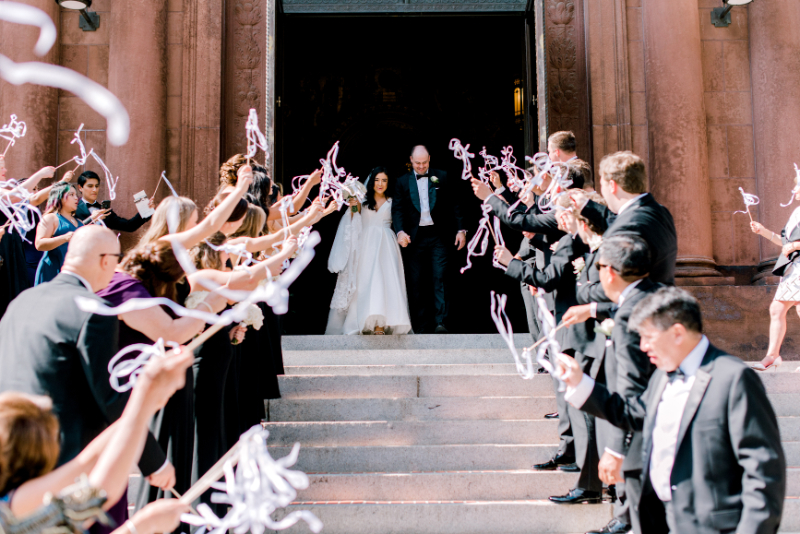 bride and groom exit the church with streamers
