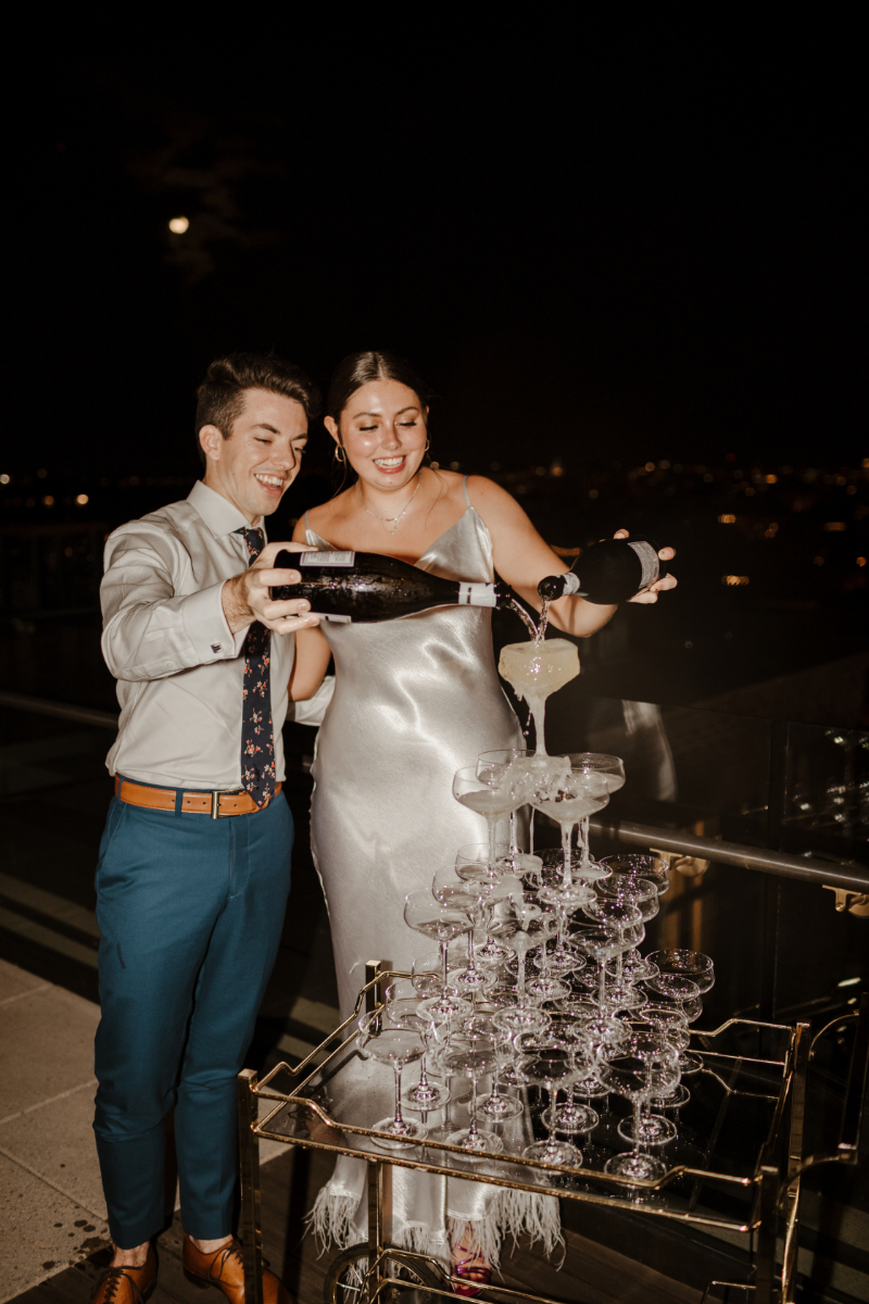 bride and groom pour champagne into champagne tower