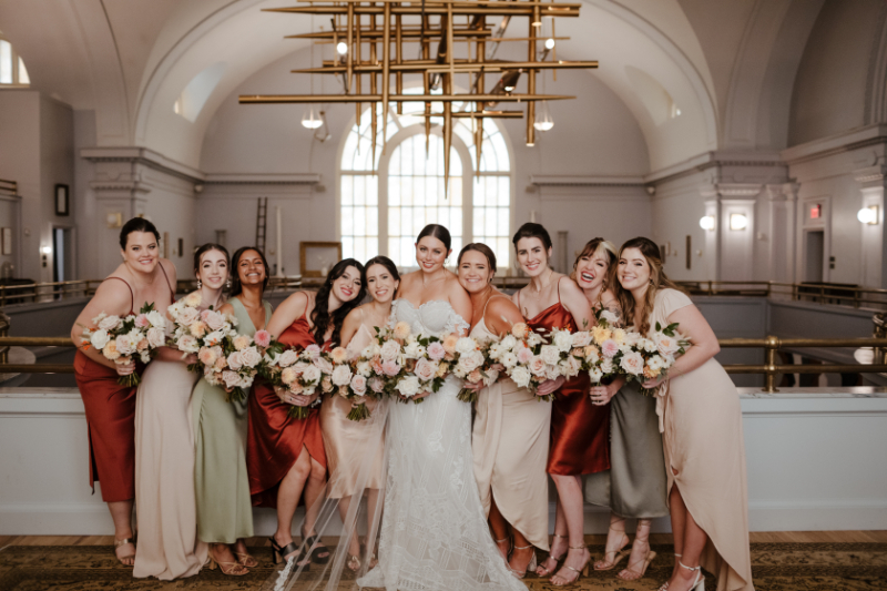 bride poses with mismatched bridesmaid dresses