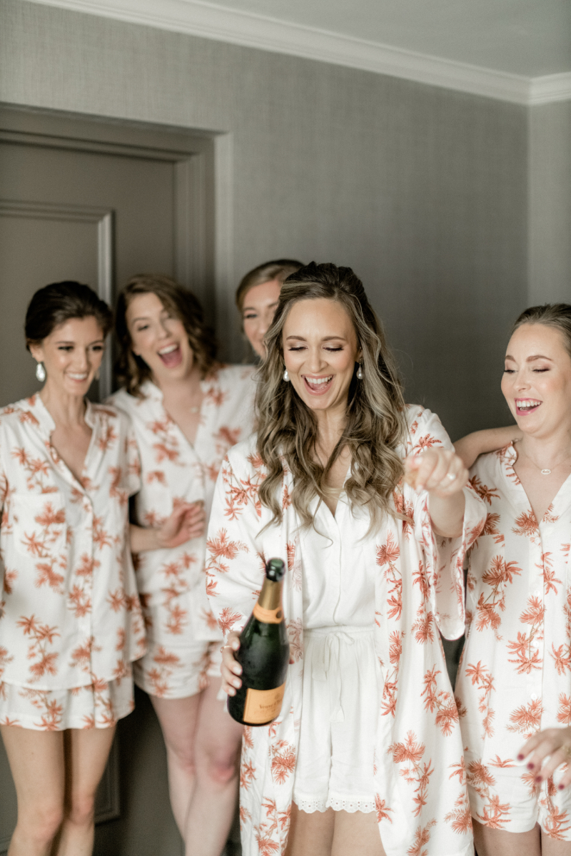 bride pops champagne with wedding party