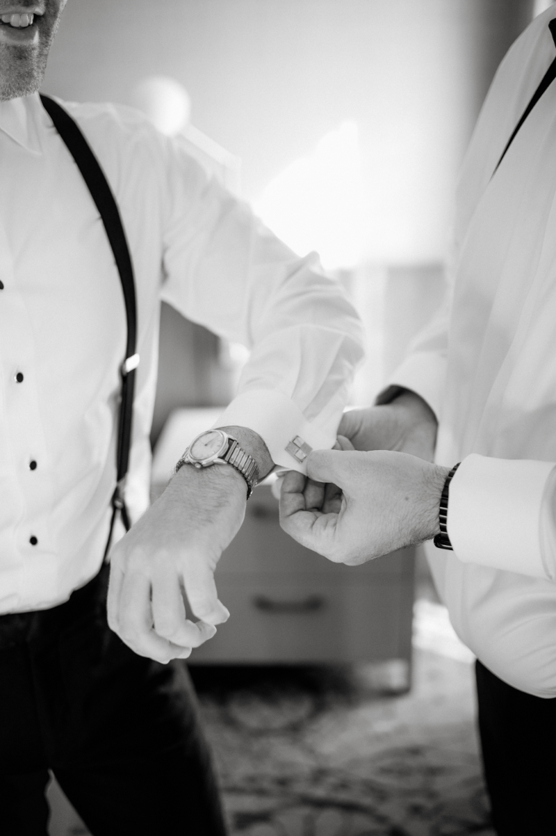 groomsmen helps groom with cufflinks