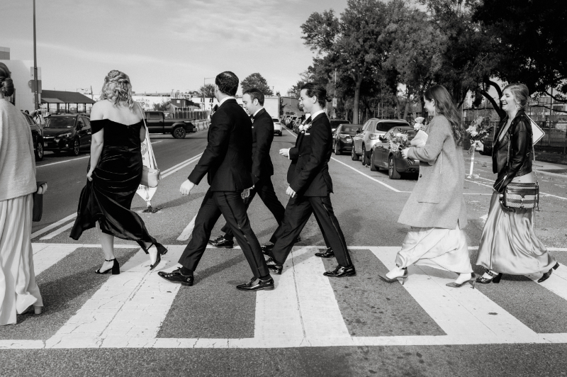 black and white photo of wedding party crossing the road