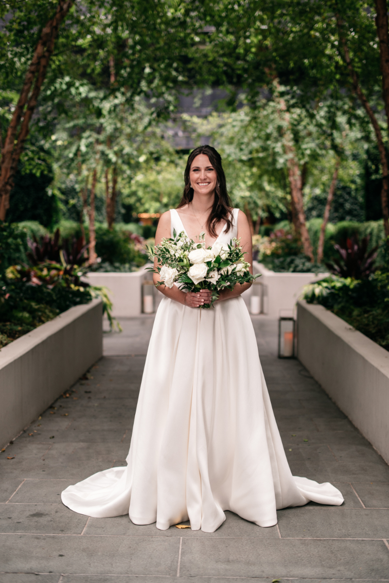bride stands in satin wedding gown