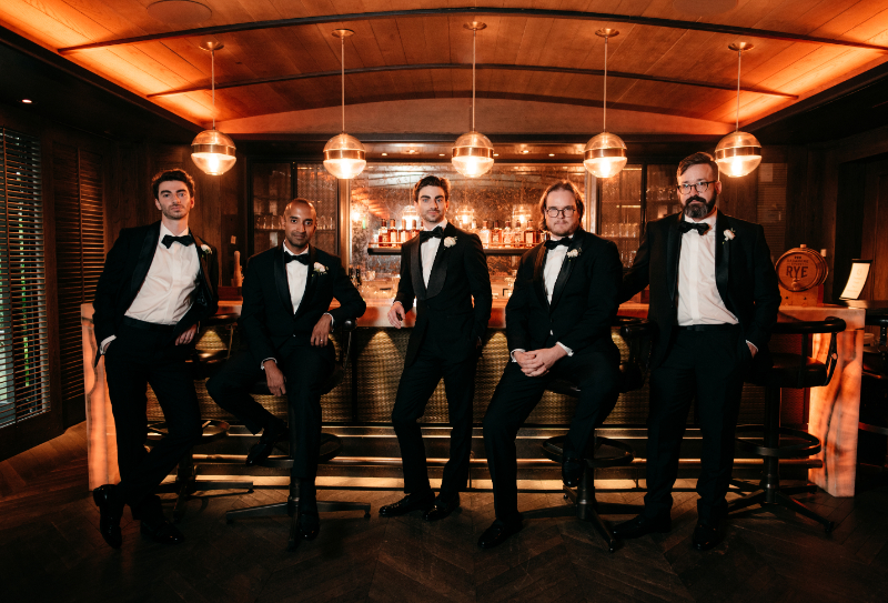 groom and groomsmen stand at hotel bar
