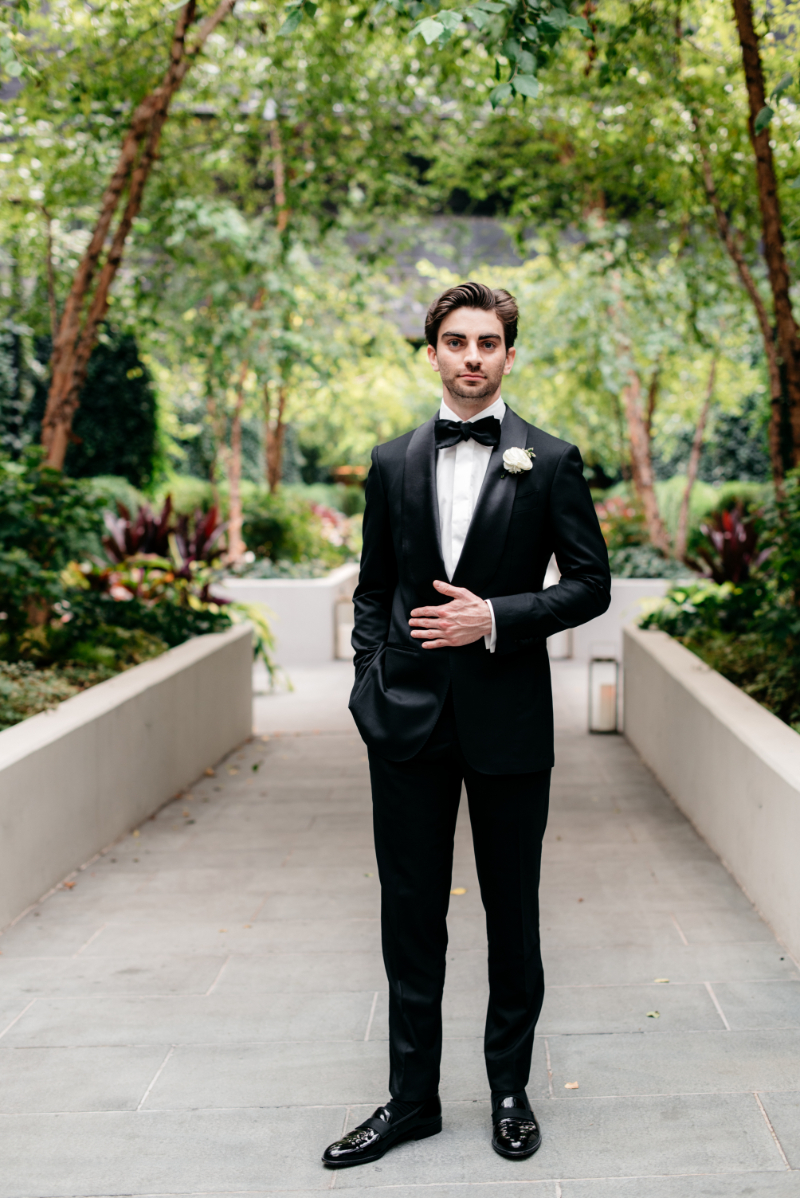 groom poses in black suit