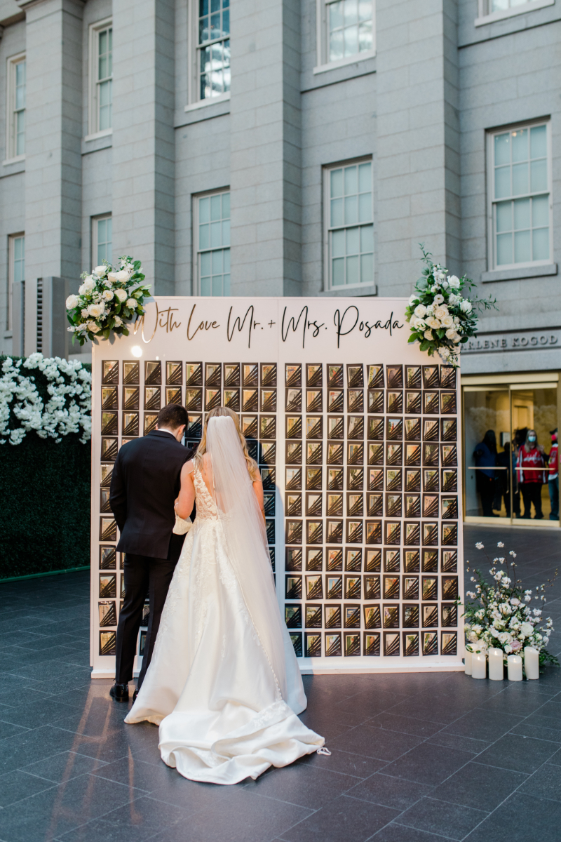 BRIDE AND GROOM IN FRONT OF PERSONALIZED ESCORT CARD WALL